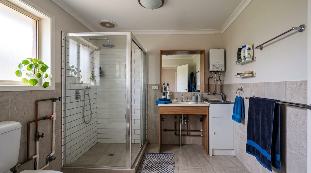 Bathroom with shower, vanity and exposed pipes