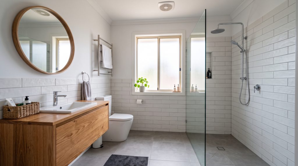 Renovated bathroom with timber vanity, round mirror and glass shower screen