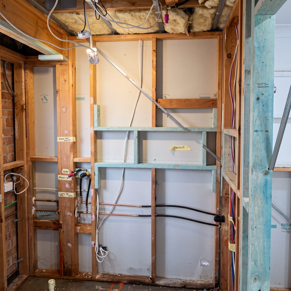 Bathroom stripped back to the frame showing pipes before renovation