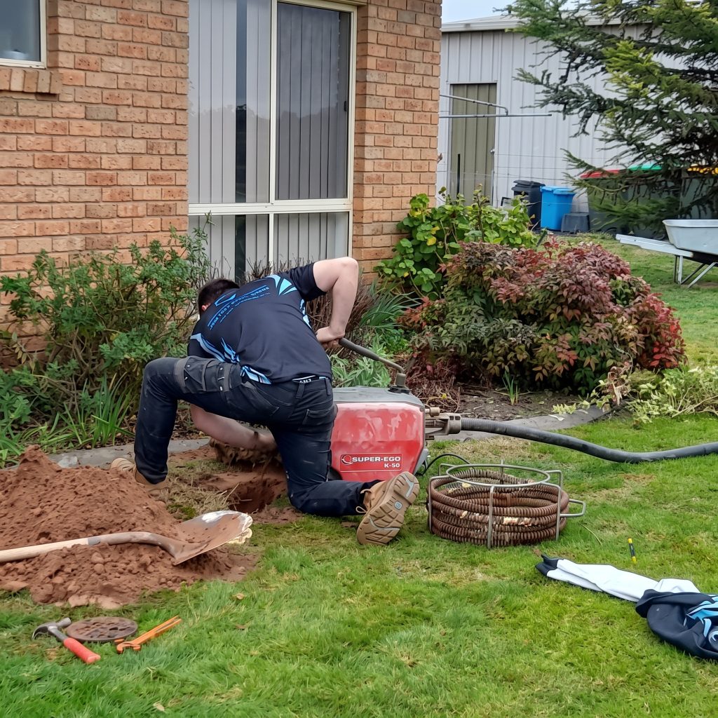 Plumber digging to reach a pipe in a backyard