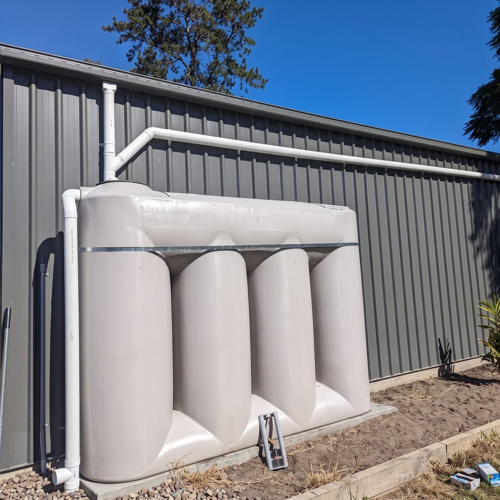 Slimline rainwater tanks installed against a steel shed